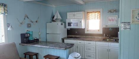 A compact kitchen with a single counter, white cabinets, and a small refrigerator.