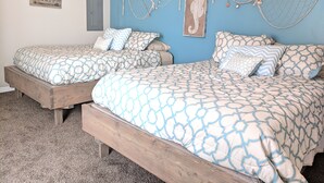 Une chambre avec deux lits, un mur bleu et des décorations sur le thème de la marine.