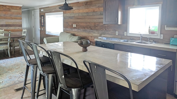 Une cuisine moderne dotée d’un grand îlot central, de touches de bois et de luminaires suspendus.