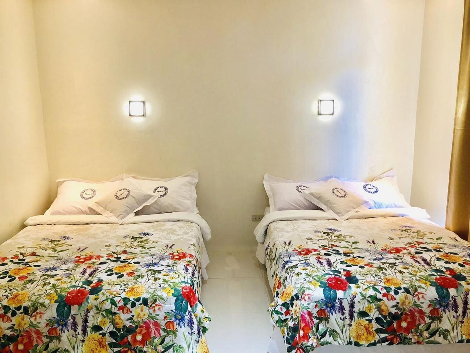 A room with two beds, each with floral bedding and matching pillows.