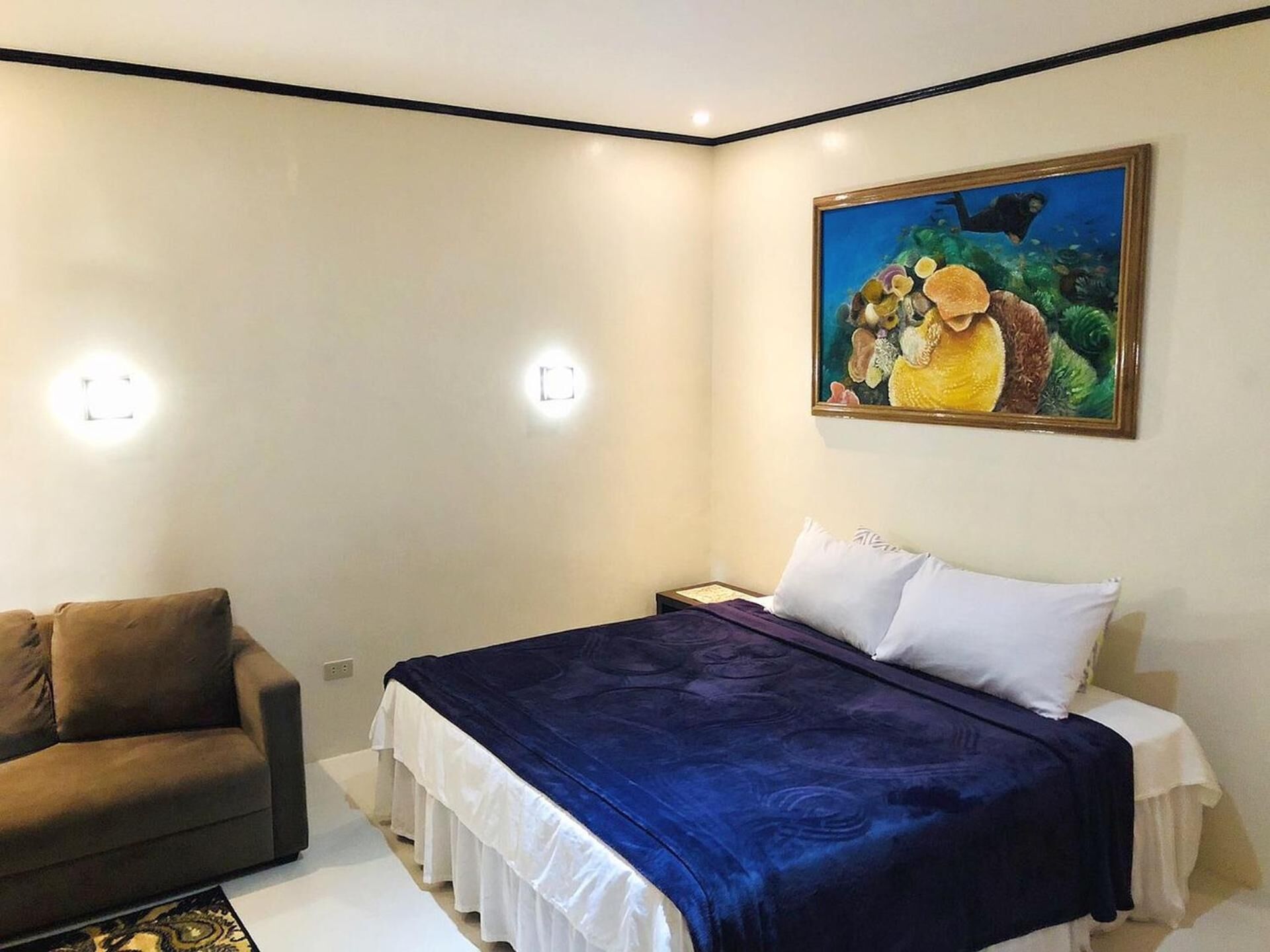 A bedroom with a bed, a nightstand, a lamp, and a painting on the wall.