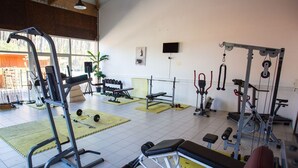Une salle de sport équipée de divers appareils d’entraînement, notamment des machines de musculation, des haltères et un banc.