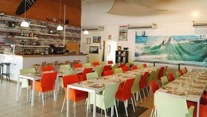 Un restaurant doté de nombreuses tables et chaises, d’un bar et d’une fresque murale représentant un surfeur sur une vague.