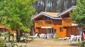 Une cabane en bois dotée de deux balcons, d’un espace extérieur aménagé pour s’asseoir et offrant une vue dégagée sur la forêt environnante.