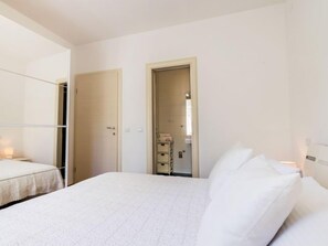 Hotellihuone, jossa on sänky, vaatekaappi ja kylpyhuone, jotka näkyvät avoimesta ovesta.