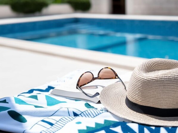 A poolside setting with a hat, sunglasses, and a towel. - Villa 2 Pools by Interhome (Brač/Sutivan)
