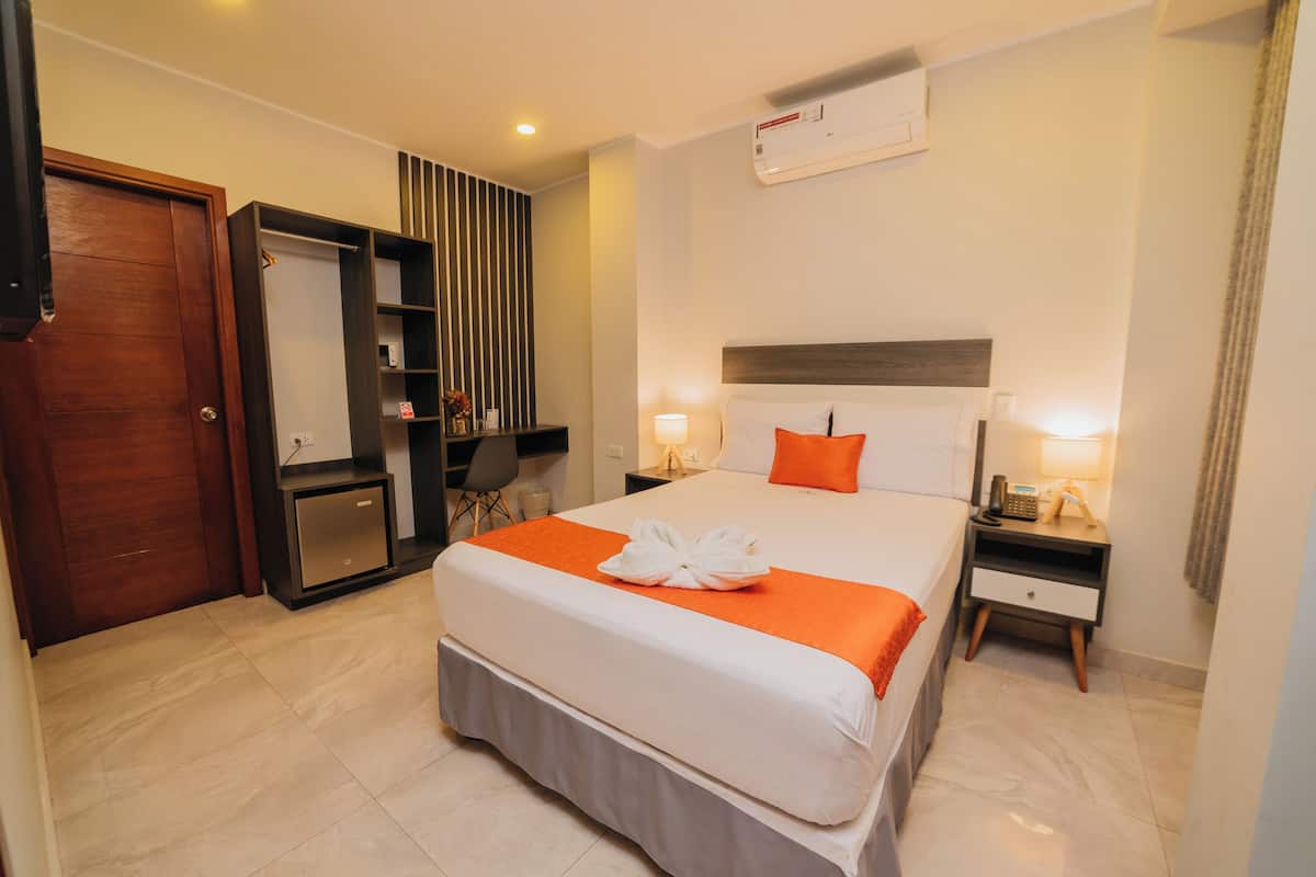 Une chambre d’hôtel comprenant un lit, des tables de chevet, une armoire, un bureau et une chaise.