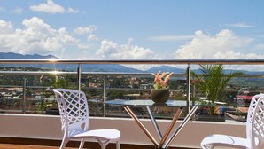 A balcony with two white chairs, a glass table, and a vase with flowers. - Palm Hotel (Tarapoto)