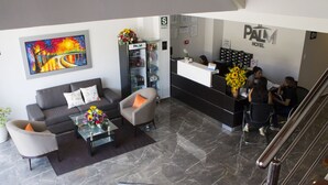 A hotel reception area with a modern design, including a reception desk, a sofa, a coffee table, and a painting on the wall. - Palm Hotel (Tarapoto)