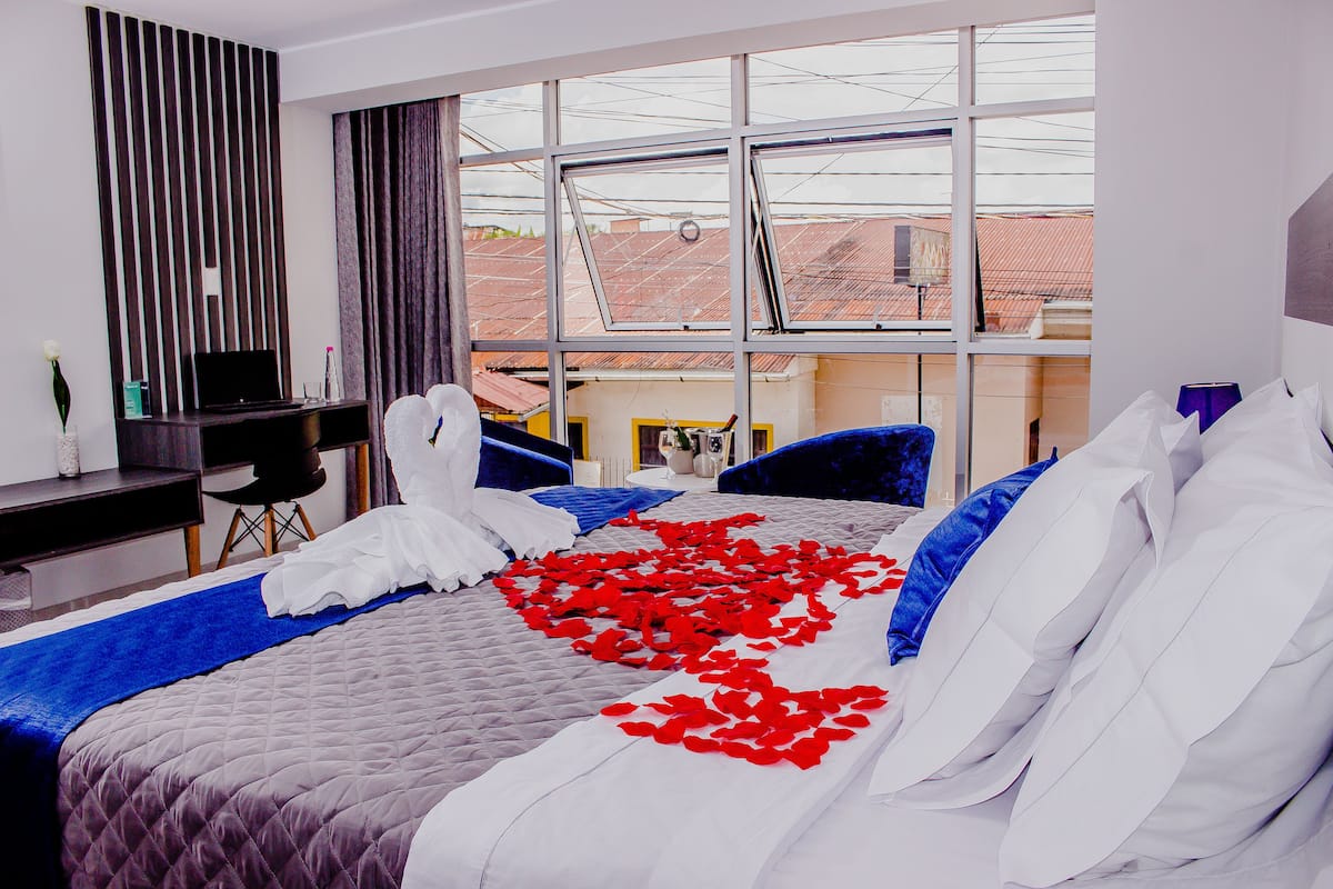 Une chambre d’hôtel avec un lit, un bureau et une grande fenêtre.