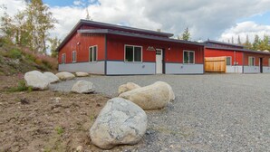 A red building with a gravel driveway and large rocks in front. - Matanuska Villa #1, Glacier Suites - Matanuska Villa #1 (Matanuska-Susitna)