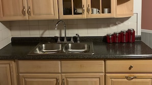A kitchen with wooden cabinets, a double sink, and a countertop with red jars. - Well-appointed with everything needed (Pawtucket)
