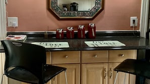 A kitchen with wooden cabinets, a tiled backsplash, and two black bar stools. - Well-appointed with everything needed (Pawtucket)