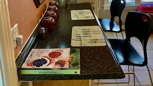 A kitchen with a long counter, a refrigerator, and a window with blinds. - Well-appointed with everything needed (Pawtucket)