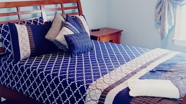 A bedroom with a bed, a nightstand, a ceiling fan, and a floral painting on the wall. - Well-appointed with everything needed (Pawtucket)