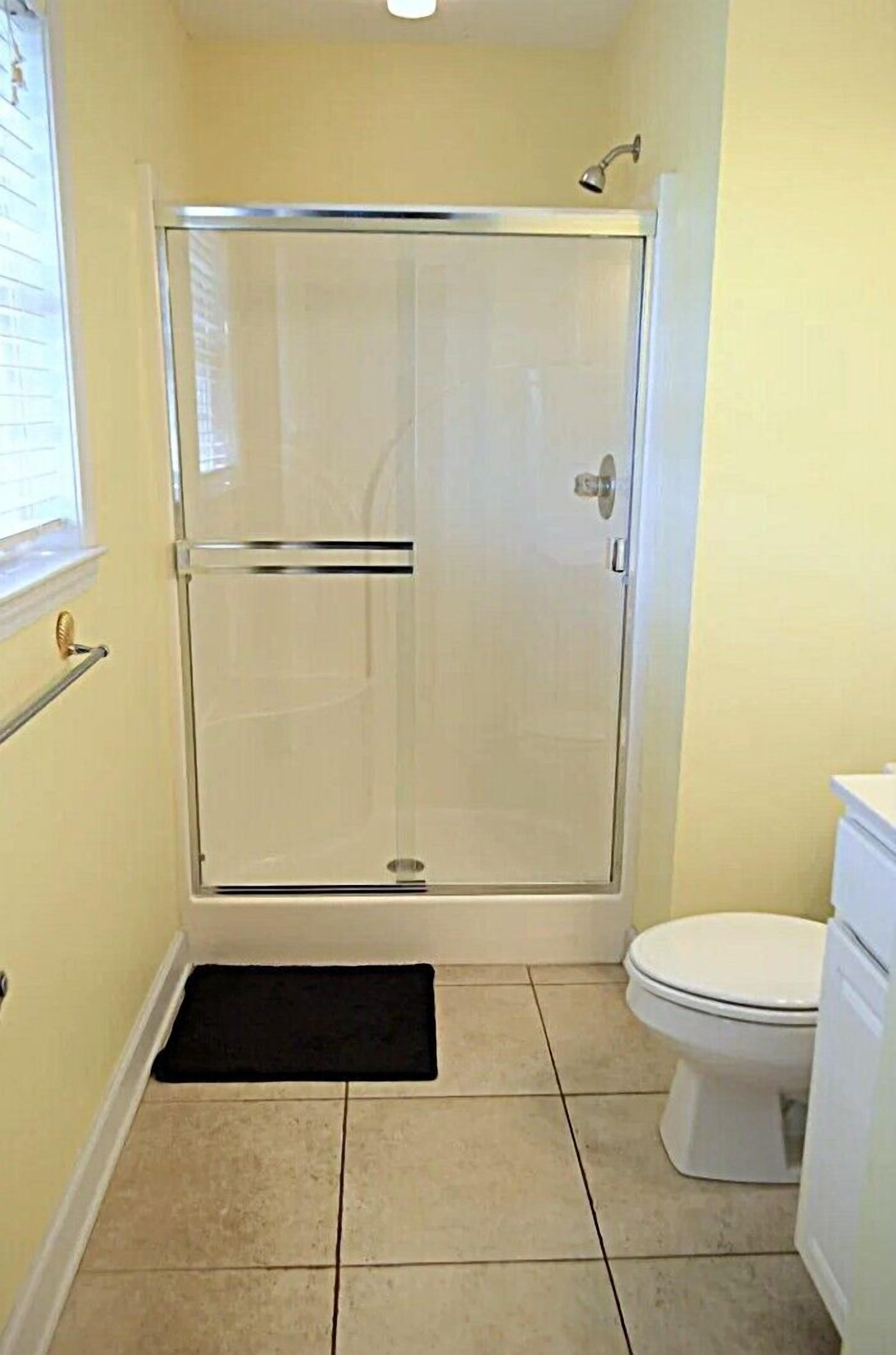 Ein Badezimmer mit Duschkabine, Toilette und kleinem Fenster.