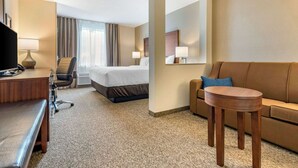 A hotel room with a bed, a desk with a chair, a sofa, a small table, and a TV. - Comfort Inn & Suites (Goderich)
