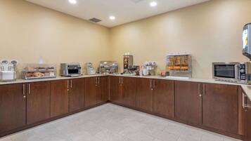 A buffet area with various food stations, including a coffee machine, a microwave, and a beverage dispenser.