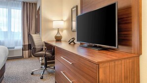 A hotel room with a wooden desk, a television, a lamp, a chair, and a bed. - Comfort Inn & Suites (Goderich)