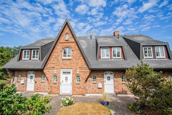 A two-story brick house with a steeply pitched roof, dormer windows, and a symmetrical facade. - Munkhoog - Munkmarsch (Munkmarsch)