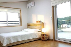 A bedroom with a bed, a bedside lamp, and a window with blinds.
