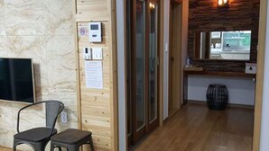 A wooden interior with a television, a chair, a wooden door, and a small table. - Sonangche (Jeju City)