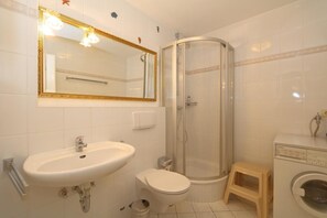 A bathroom with a sink, toilet, shower, and a washing machine. - Mecking Munkmarsch<br>The Mecking apartment is a lovingly furnished, fully equipped, modern and quietly located vacation home. (Munkmarsch)