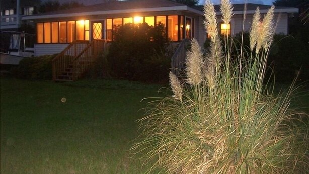 A house with a well-lit porch and a grassy lawn. - Cottage:  3005 Palmetto Blvd. (Edisto Beach)