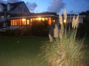 Ein Haus mit einer gut beleuchteten Veranda und einem Rasen.