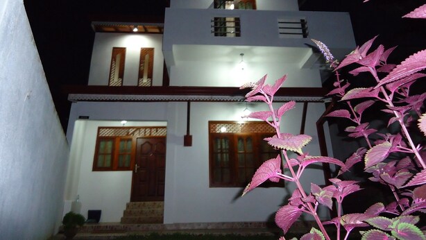 A two-story building with a white facade, wooden doors, and a staircase leading to the entrance. - 1 and 1 (Malimbada)