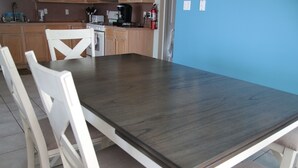 Un espace repas comprenant une table rectangulaire et quatre chaises blanches.