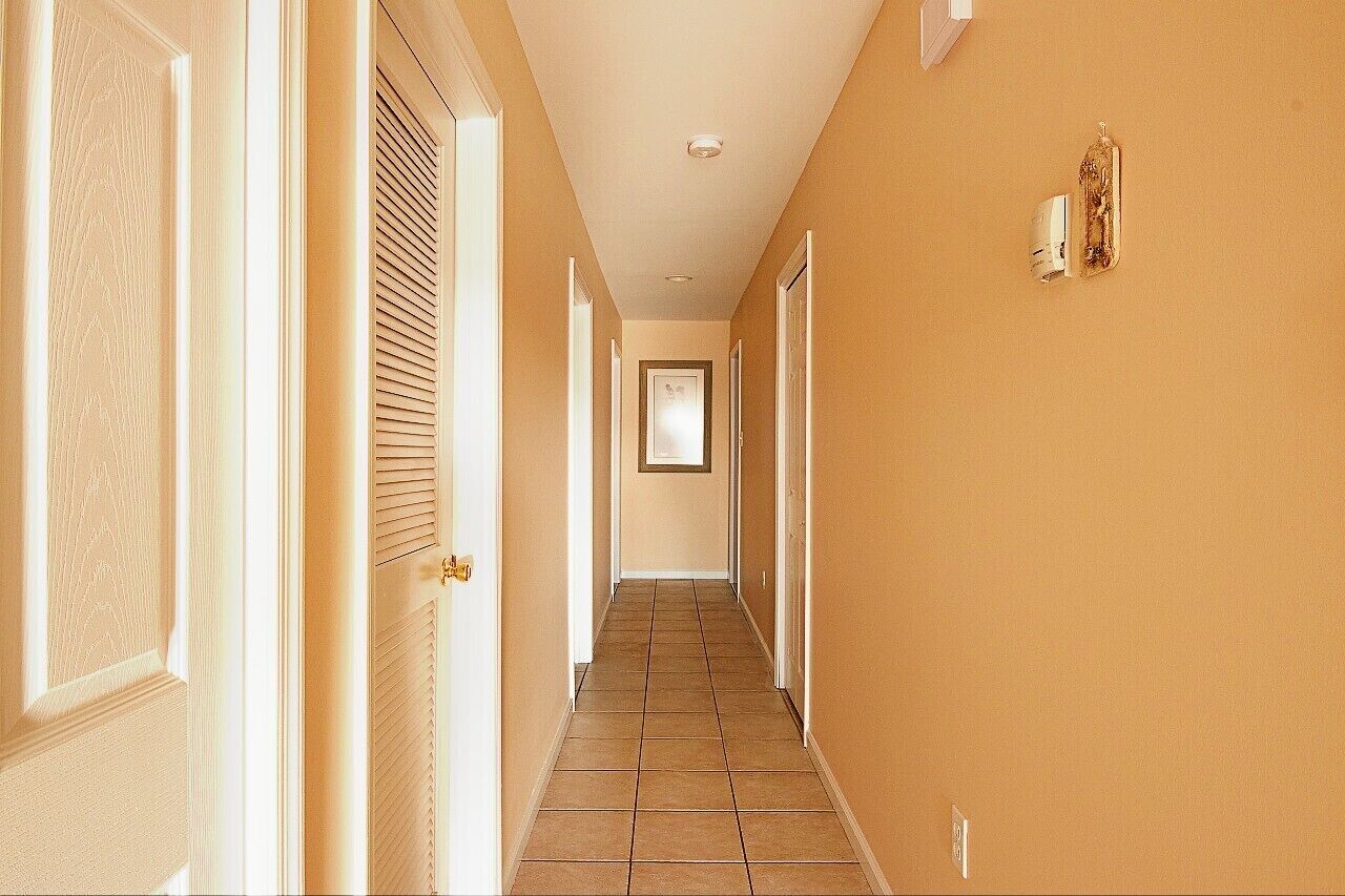 Un couloir doté d’un sol carrelé, de murs de couleur beige et de portes de part et d’autre.