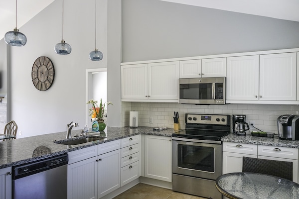 Beaming white cabinetry; Stainless steel appliances