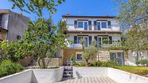 Ein zweistöckiges Gebäude mit Balkon, Steinaußenwand und einem gepflasterten Innenhof mit Stufen, die zu einer Tür führen.