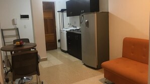 Ein kompakter Wohnbereich mit Küchenzeile, einem Essbereich mit Tisch und Stühlen sowie einer Couch.