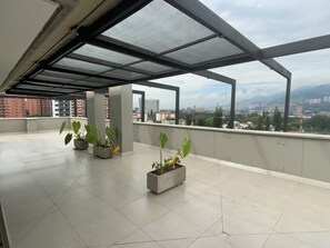 A spacious rooftop terrace with a clear view of the cityscape and mountains in the distance.