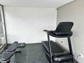 A room with a treadmill, a stationary bike, and a bench.