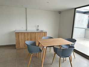 A modern kitchen with a wooden island, a sink, and a dining area with a table and chairs.