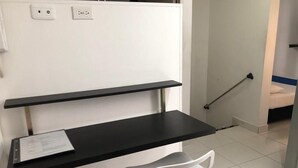 Et lille, privat kontorområde med skrivebord, to stole og en hvid skærm med stikkontakter.