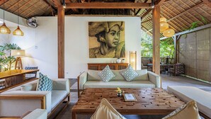 Un amplio espacio al aire libre con una mesa de madera, sofás acolchados y una obra de arte grande colgada en la pared.