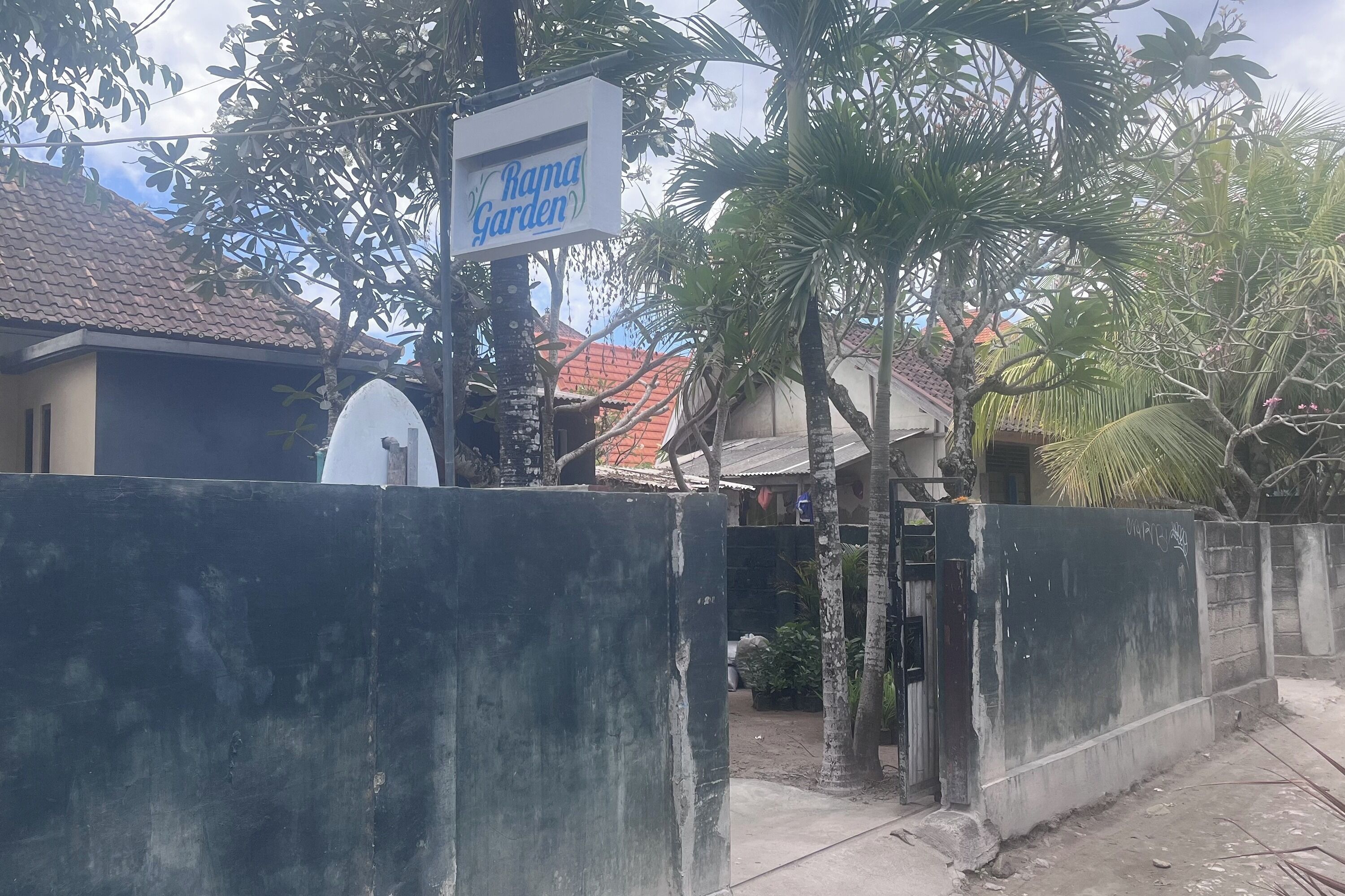 Un área vallada con un letrero que indica Rama Garden, una antena parabólica y un muro de concreto.