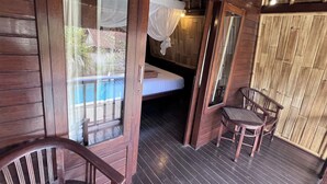 Eine Holzhütte mit einem Bett, einem Stuhl und einem Fenster mit Blick auf einen Pool.