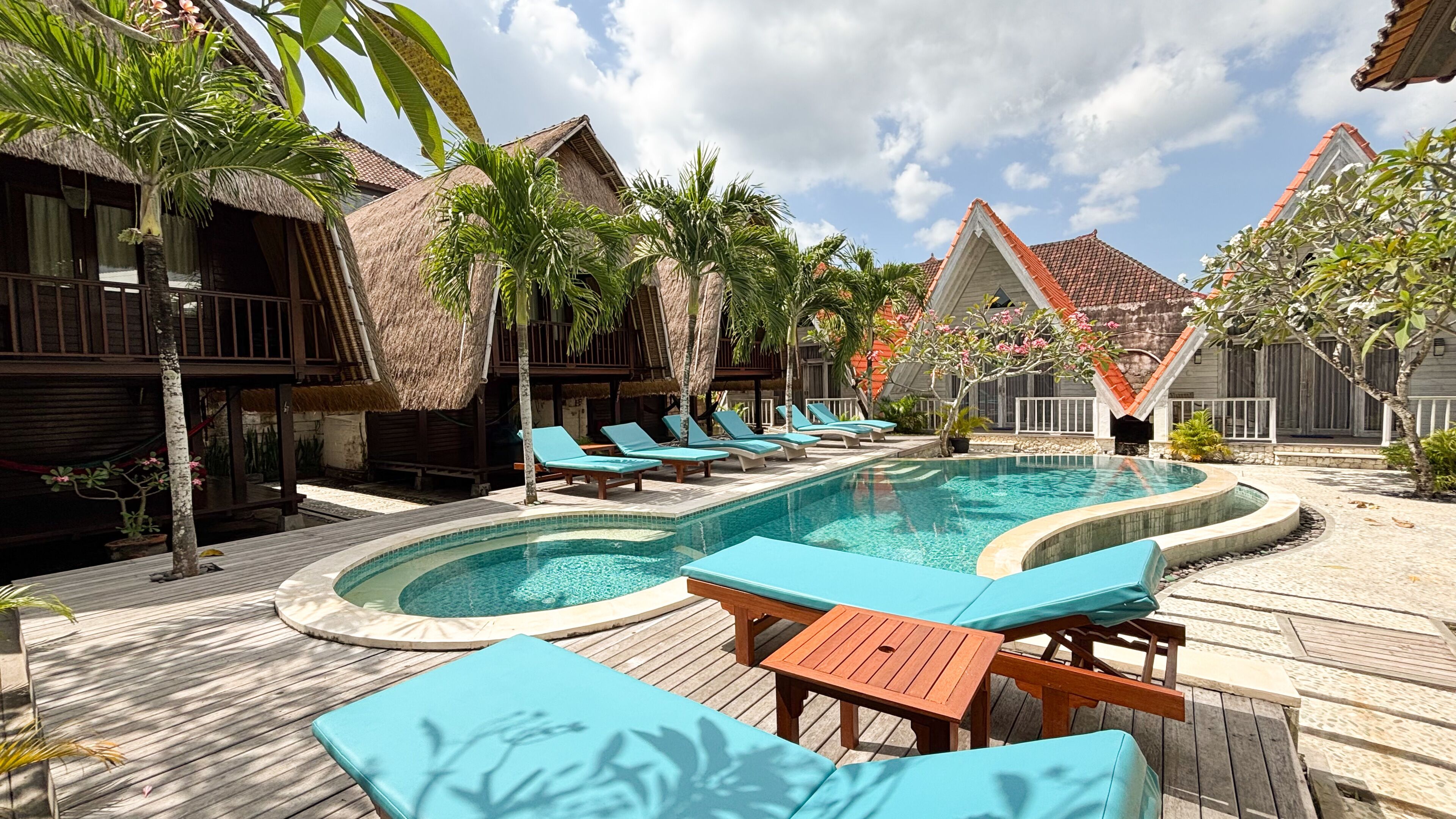 A pool area with lounge chairs and a wooden deck.