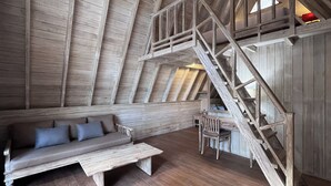 Ein Loft-Zimmer mit einer Holztreppe, einer Couch und einem Esstisch.