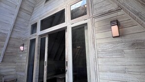 Ein Holzhaus mit großen Fenstern und einer Bank vor der Tür.