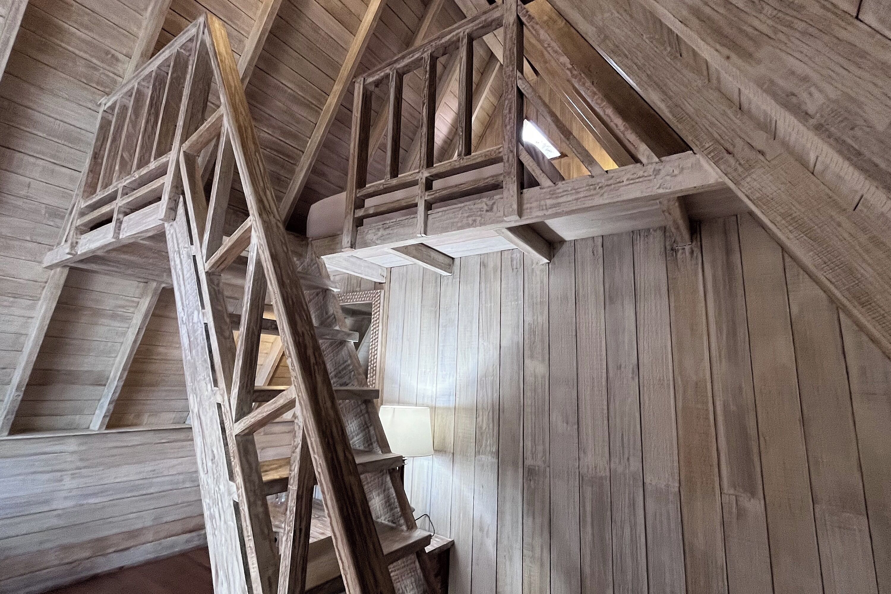 Eine Holztret Treppe mit Geländer, die zu einem Balkon führt.