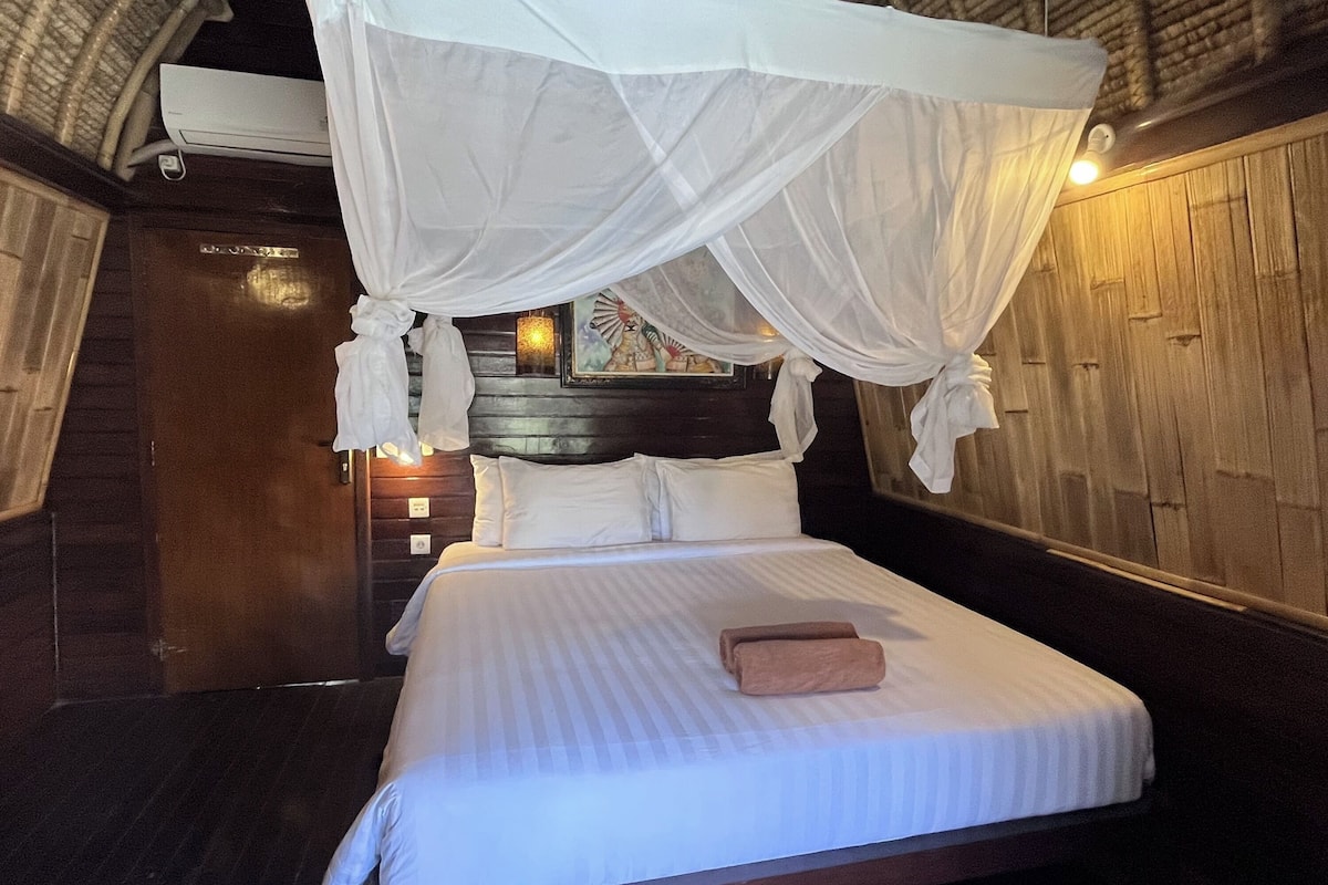 A bed with a canopy, a wooden headboard, and a wall-mounted air conditioning unit.