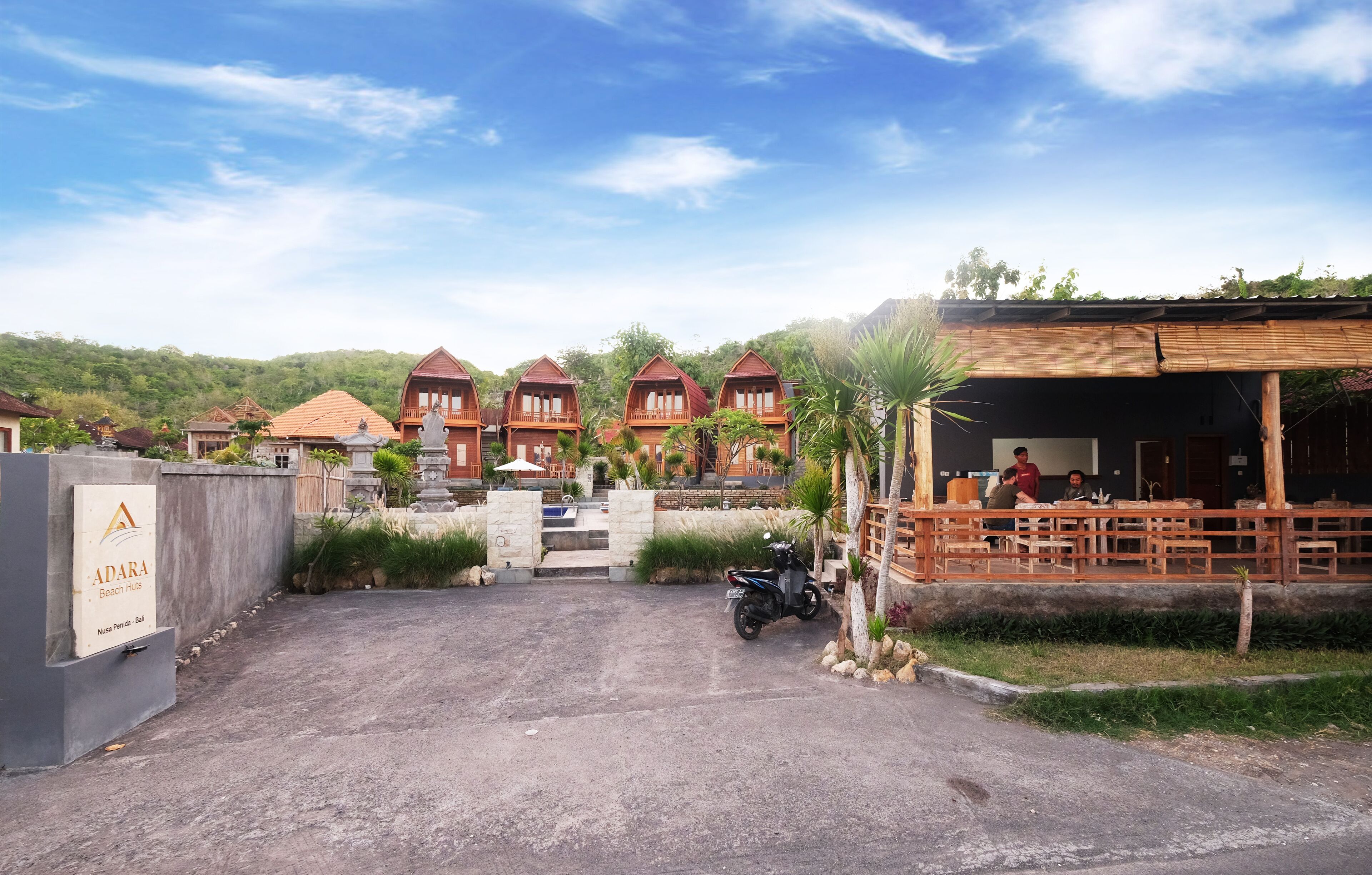 A resort with multiple bungalow-style buildings, a covered dining area, and a paved entrance.