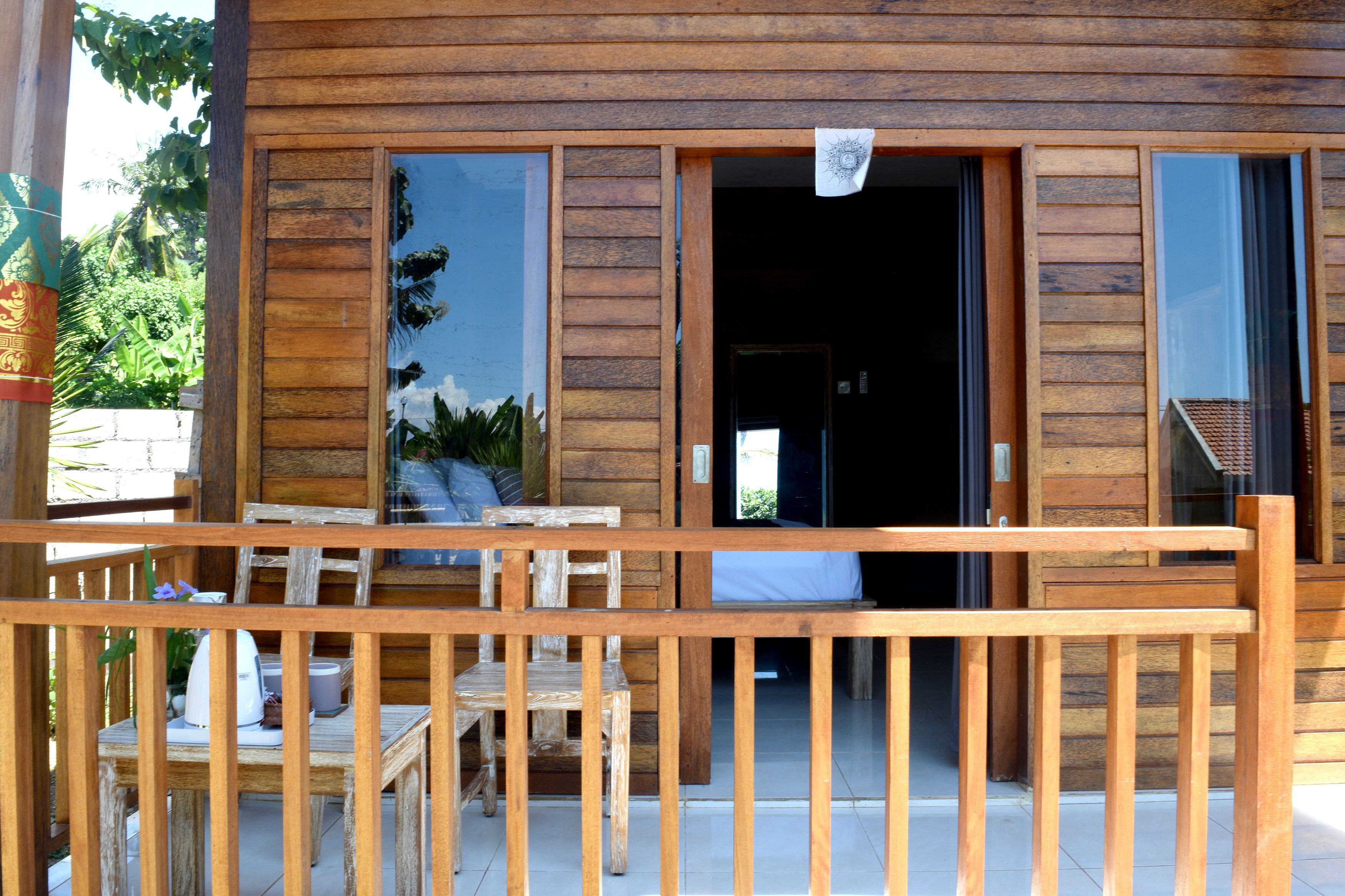 A wooden cabin with a balcony, a dining area, and a visible entrance.