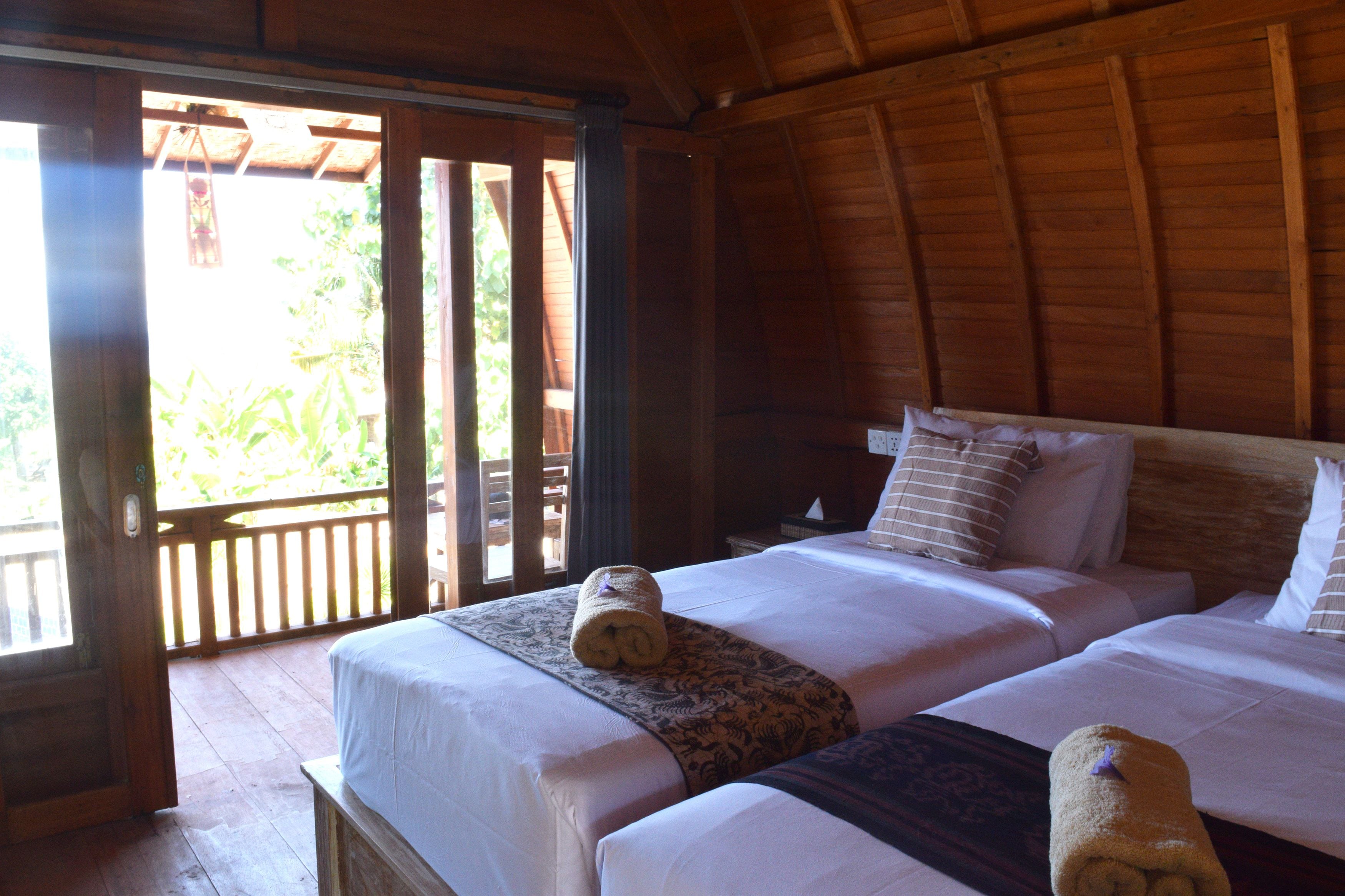 Una habitación de madera con dos camas, cada una con ropa blanca y almohadas estampadas.